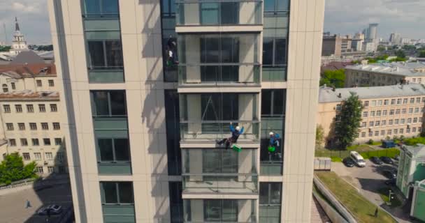 Lavadoras de ventanas en un edificio de oficinas. Escalador industrial - Limpieza de fachadas. Fotografía aérea dron de aire — Vídeo de stock