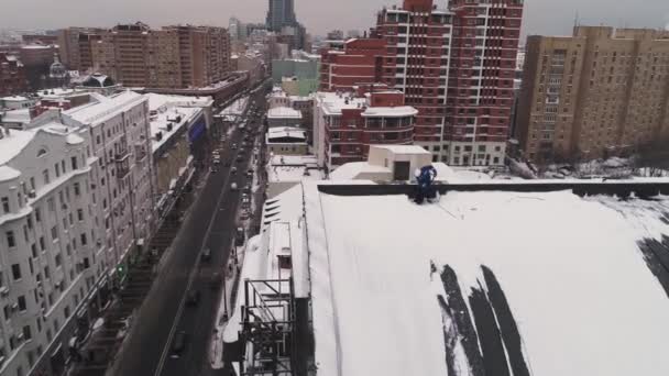 工业登山者从莫斯科堆积如山的雪中清理了一个屋顶。空中. — 图库视频影像