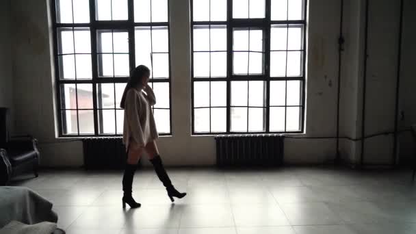 ステディカムは、仕事に行く途中で素晴らしい気分で若い美しいアジアの女の子のショット。●アジアの外観のモデル、長いセーターで美しいロフトの窓の前を歩きます。スローモーション。一般 — ストック動画