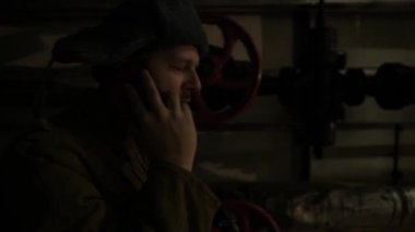 Kulak lık şapkalı Rus adam, karanlık bir bodrumda telefonda konuşuyor ve ulusal öneme sahip konulara karar veriyor..