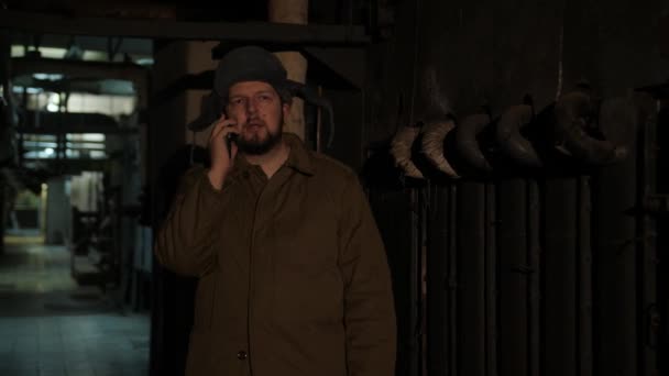Uomo russo in cappello con paraorecchie, che parla al telefono in un seminterrato buio e decide questioni di importanza nazionale . — Video Stock