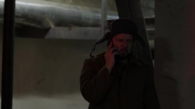 Tavandaki lambayı çeviriyor. Kulaklıklı şapkalı Rus hacker bodrumda telefonda konuşuyor. Yoğun yapılı bir adam. Rus dehası.