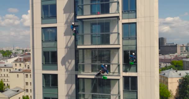 Laveuses de fenêtres sur un immeuble de bureaux. Escalade industrielle - Nettoyage de façade. Photographie aérienne drone aérien — Video