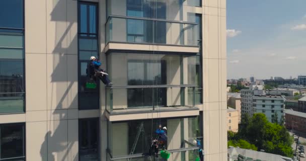 Fönstertvättmaskiner på en kontorsbyggnad. Industriell klättrare - fasadrengöring. Flygfoto luft drönare — Stockvideo