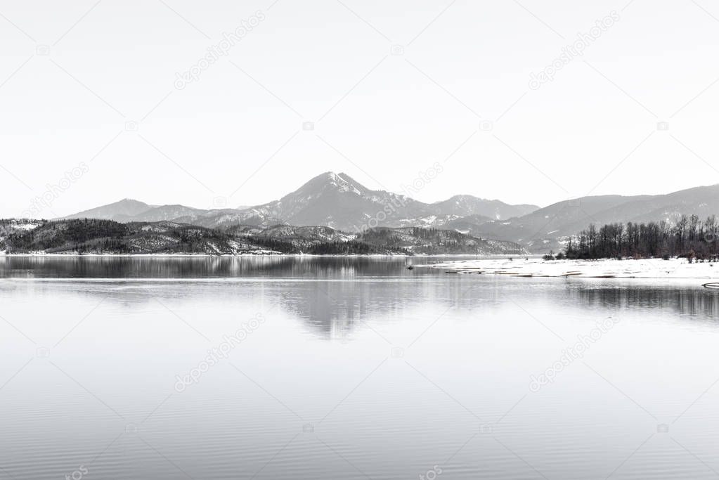 Tranquil wintry scenery. Landscape, Black snowy mountain, clear sky on lake at a winter day, Greece.Vintage look photo