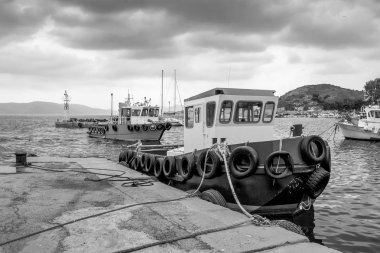 Bir yağmurlu kış gün ağır bir gökyüzünün altında. Küçük limandaki balıkçı tekneleri. Pachi, Yunanistan