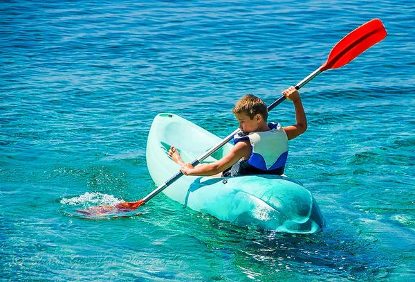 Chico Joven Remando Duro Kayak Con Salpicaduras Cerca Del Acantilado — Foto de Stock