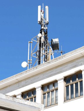 Cep telefonu telekomünikasyon antenler ve açık mavi gökyüzü karşı binasında Tekrarlayıcı