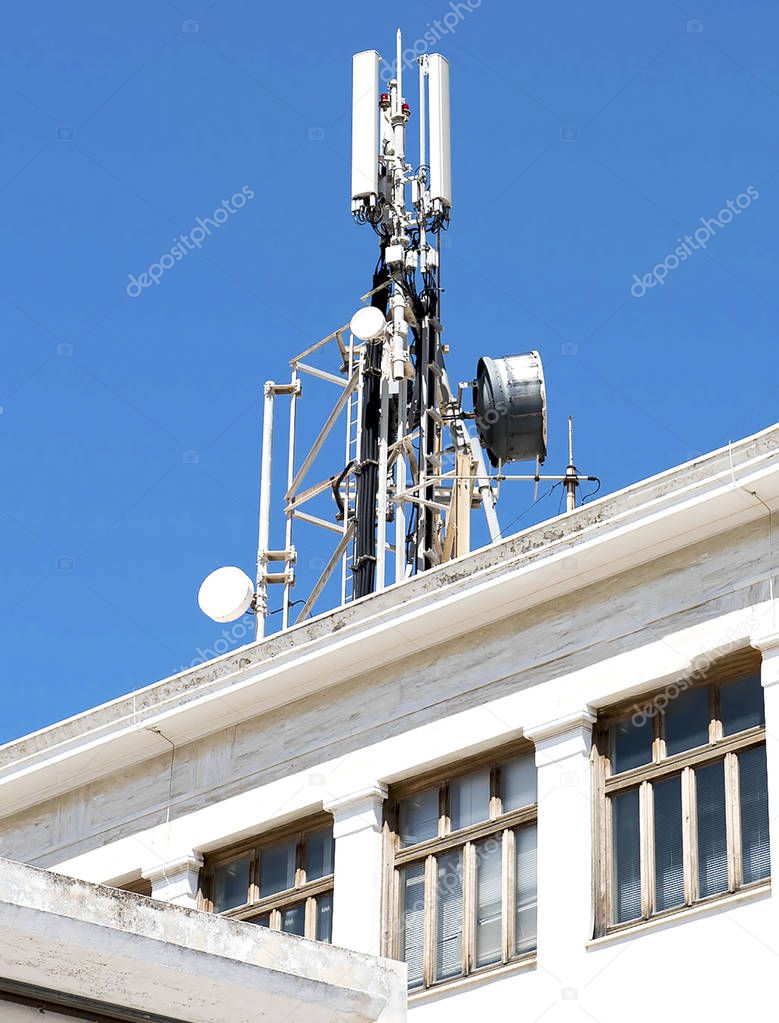 Cell phone telecommunications antennas and repeaters on building against clear blue sky