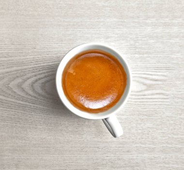 White cup with espresso coffee on wooden table for background
