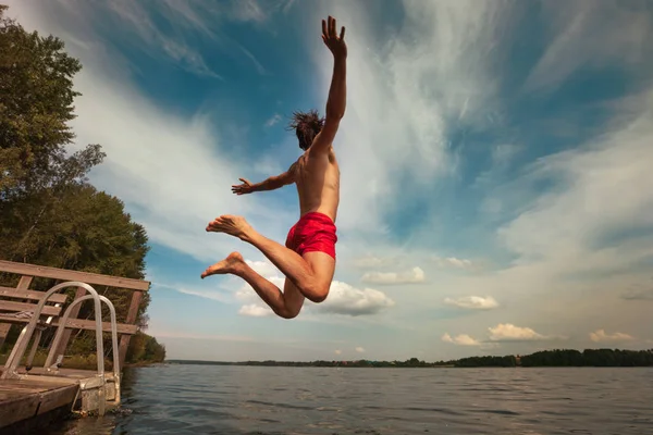 Young man jumping into water. Outdoor adventure lifestyle.