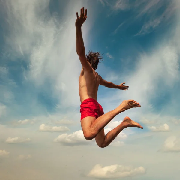 Молодой человек прыгает в воду. Летний стиль жизни — стоковое фото