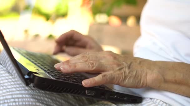 Widok z bliska na ręce. Dorosła kobieta pracująca na zewnątrz na laptopie, uśmiechnięta babcia w średnim wieku pracująca zdalnie na komputerze. — Wideo stockowe