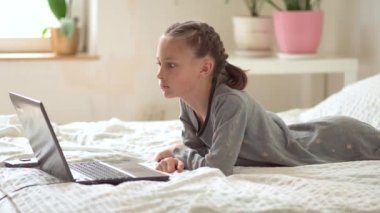 Tatlı çocuk eğitim için dizüstü bilgisayar kullanıyor, online öğrenim görüyor, evde eğitim görüyor. Kızın evde ödevi var..