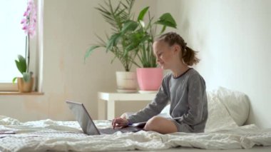 Tatlı çocuk eğitim için dizüstü bilgisayar kullanıyor, online öğrenim görüyor, evde eğitim görüyor. Kızın evde ödevi var..