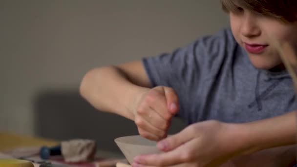 De vervaardiging van keramiek. Kleine jongen beeldhouwt uit klei — Stockvideo