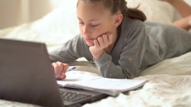 Tatlı çocuk eğitim için dizüstü bilgisayar kullanıyor, online öğrenim görüyor, evde eğitim görüyor. Kızın evde ödevi var..