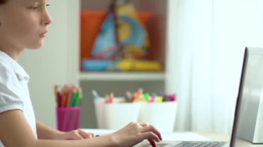 Tatlı çocuk eğitim için dizüstü bilgisayar kullanıyor, online öğrenim görüyor, evde eğitim görüyor. Kızın evde ödevi var..