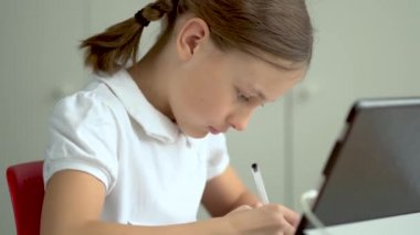 Tatlı çocuk eğitim için dizüstü bilgisayar kullanıyor, online öğrenim görüyor, evde eğitim görüyor. Kızın evde ödevi var..