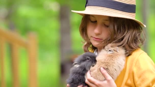 O fată drăguţă se joacă cu un iepure adevărat. Copiii se joaca cu animalele de companie . — Videoclip de stoc