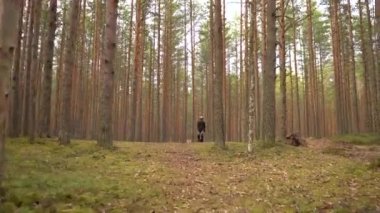 Genç adam ekolojik elektrik nakliyesine biniyor. Yetişkin tek tekerlekli bisiklet sürüyor, ormanda elektrik tekerleğini dengeliyor.