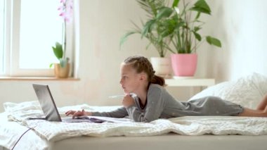 Tatlı çocuk eğitim için dizüstü bilgisayar kullanıyor, online öğrenim görüyor, evde eğitim görüyor. Kızın evde ödevi var..