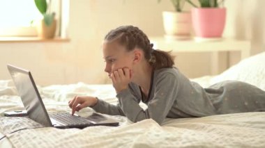 Tatlı çocuk eğitim için dizüstü bilgisayar kullanıyor, online öğrenim görüyor, evde eğitim görüyor. Kızın evde ödevi var..