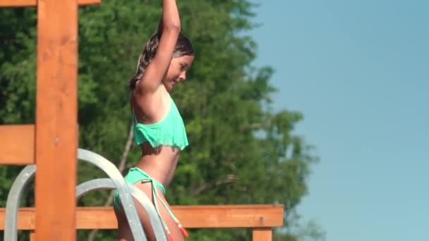 Mädchen im Neoprenanzug springen von Holzsteg in den See. Spaß am Sommertag. — Stockvideo