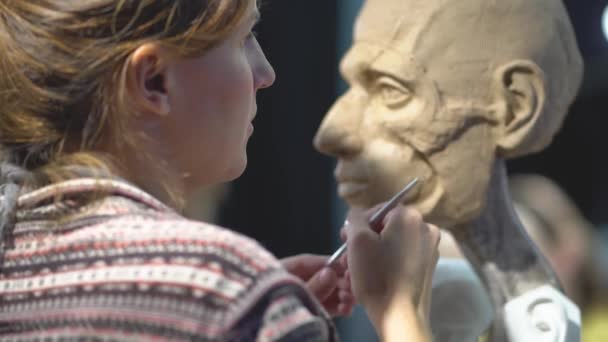 Mujer escultora trabajando en una escultura de una cabeza humana. — Vídeos de Stock