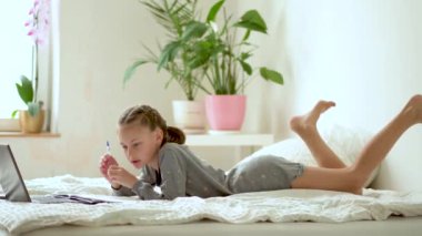 Tatlı çocuk eğitim için dizüstü bilgisayar kullanıyor, online öğrenim görüyor, evde eğitim görüyor. Kızın evde ödevi var..