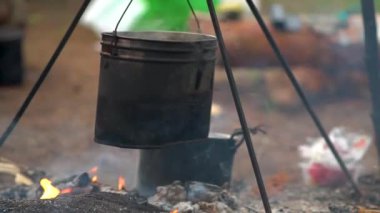 Kamp ateşinde yemek hazırlıyorum. Lezzetli taze çorbalı çaydanlık ateşte yanıyor.