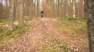 Genç adam ekolojik elektrik nakliyesine biniyor. Yetişkin tek tekerlekli bisiklet sürüyor, ormanda elektrik tekerleğini dengeliyor.