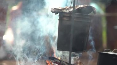 Kamp ateşinde yemek hazırlıyorum. Lezzetli taze çorbalı çaydanlık ateşte yanıyor.