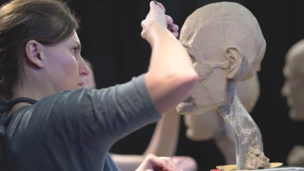 Woman sculptor at work on a sculpture of a human head. — Stock Video