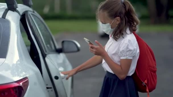 Leuke leerlingen die smartphones gebruiken op de basisschool. Jongen en meisje in veiligheid maskers met gadgets in hun handen. — Stockvideo