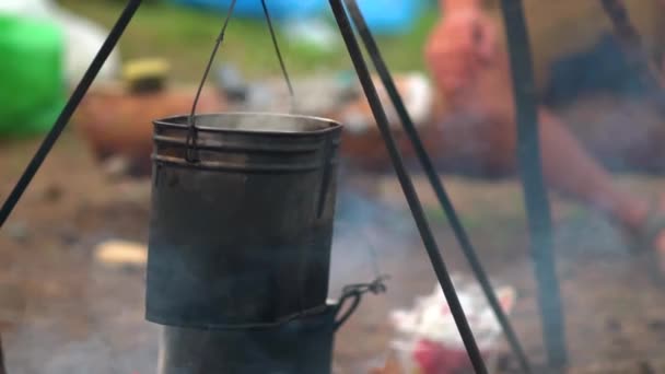 Preparando comida en fogata. Hervidor de agua con deliciosa sopa fresca en llamas en el humo — Vídeo de stock