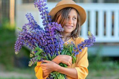 Gülümseyen bir kız elinde güzel bir buket lupin tutuyor..