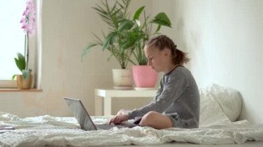 Tatlı çocuk eğitim için dizüstü bilgisayar kullanıyor, online öğrenim görüyor, evde eğitim görüyor. Kızın evde ödevi var..