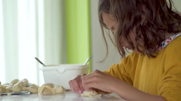 Dítě dělá knedlíky. Dívka vyvalit těsto a plísně manti s rukama — Stock video