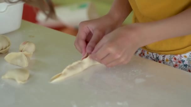 Kind maakt knoedels. Meisje rol het deeg uit en schimmel manti met haar handen — Stockvideo