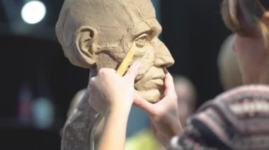 Kadın heykeltraş, insan kafası heykeli üzerinde çalışıyor..