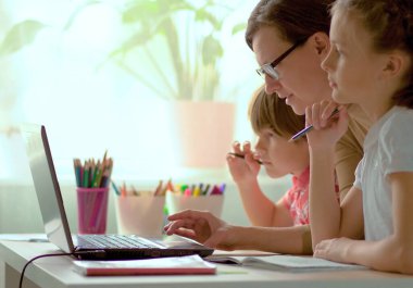 Sevimli çocuklar eğitim için dizüstü bilgisayar, online çalışma, evde eğitim için kullanırlar. Oğlan ve kızın uzaktan öğrenme ödevleri var. Evde eğitim kavramı