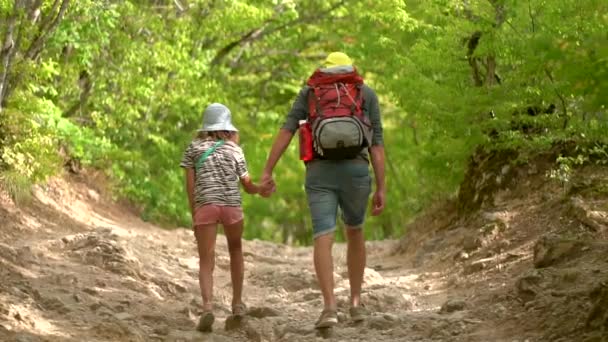 Sırt çantalı bir adam dağ yolunda kız ve oğlanla yürüyor. Seyahat tarzı konsept macera yaz tatilleri. Mutlu aile gezintisi kırsalda — Stok video