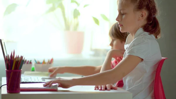Милі діти використовують ноутбук для освіти, онлайн-вивчення, домашнього навчання. Хлопчик і дівчинка мають домашнє завдання на відстані, навчаючись. Концепція домашньої освіти — стокове фото