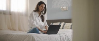 Evden bilgisayarını tamir ederken gülümseyen genç bir kadın. Ağır çekim, BMPCC 4K