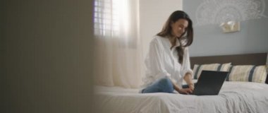 Evden bilgisayarını tamir ederken gülümseyen genç bir kadın. Ağır çekim, BMPCC 4K