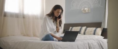 Evden bir dizüstü bilgisayarla çalışırken telefonda biriyle konuşan bir kadın. Ağır çekim, BMPCC 4K