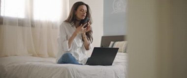 Evden bir dizüstü bilgisayarla çalışırken telefonda biriyle konuşan bir kadın. Ağır çekim, BMPCC 4K