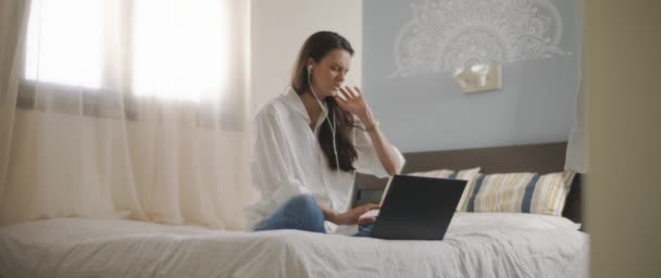 Młoda Kobieta Rozmawiająca Kimś Przez Słuchawki Podczas Pracy Nad Laptopem — Wideo stockowe