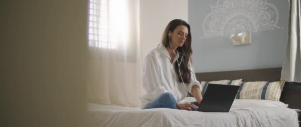 Młoda Kobieta Rozmawiająca Kimś Przez Słuchawki Podczas Pracy Nad Laptopem — Wideo stockowe